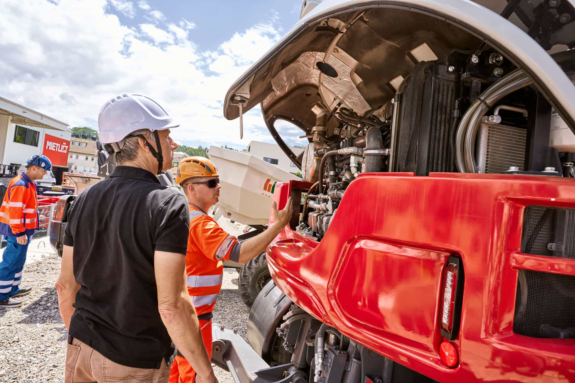 Schulungsteilnehmer begutachten den Motorraum eines Fahrzeugs im Adepto Ausbildungszentrum